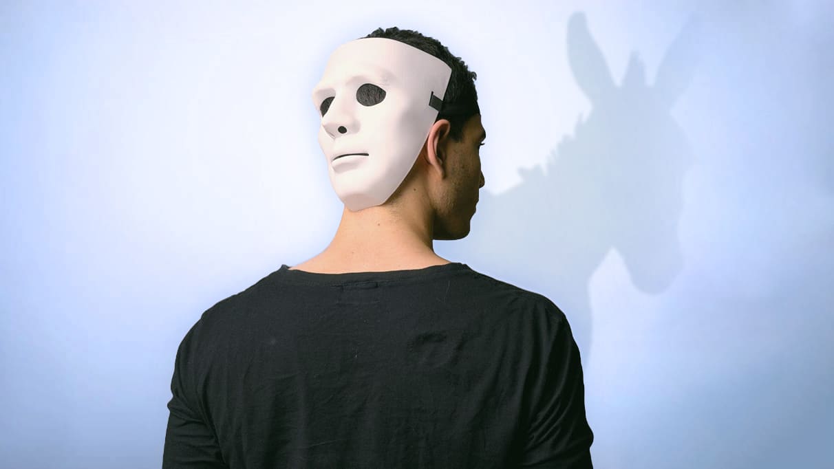 Guy with back turned with Mask worn at the back of head with a donkey shadow in the background